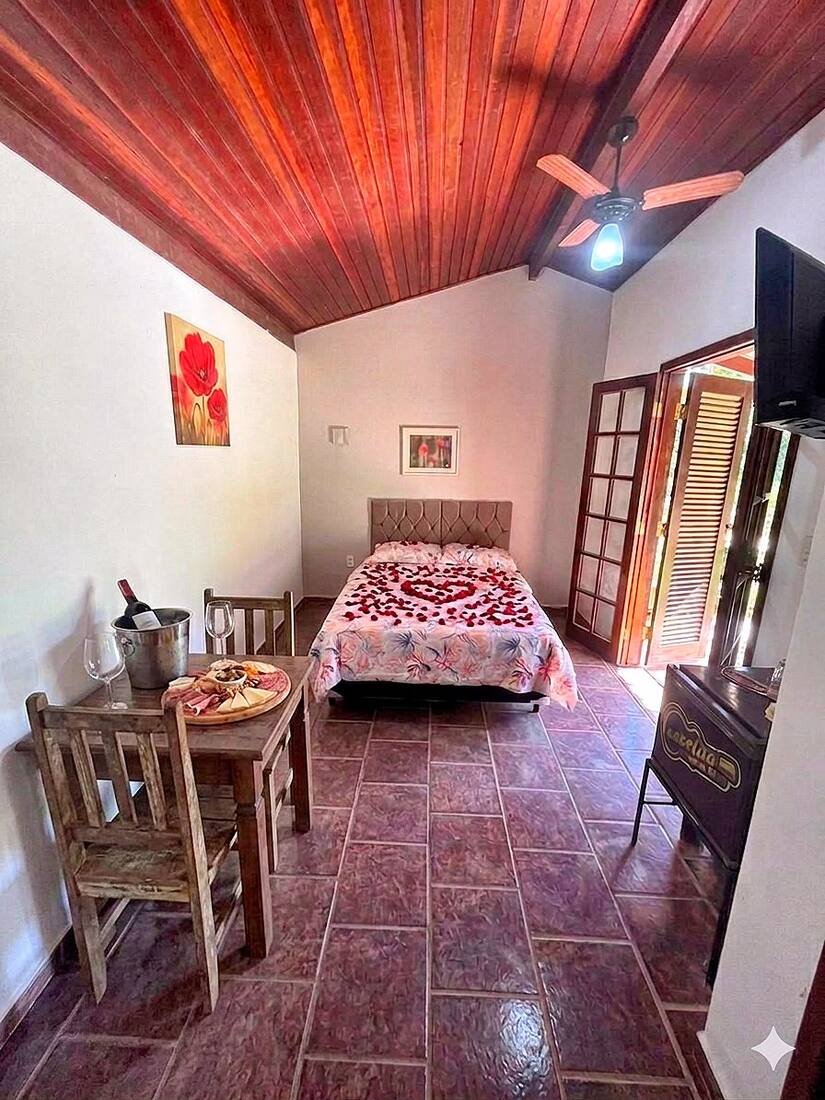 Suíte casal decorada com pétalas de rosa e mesa com espumante